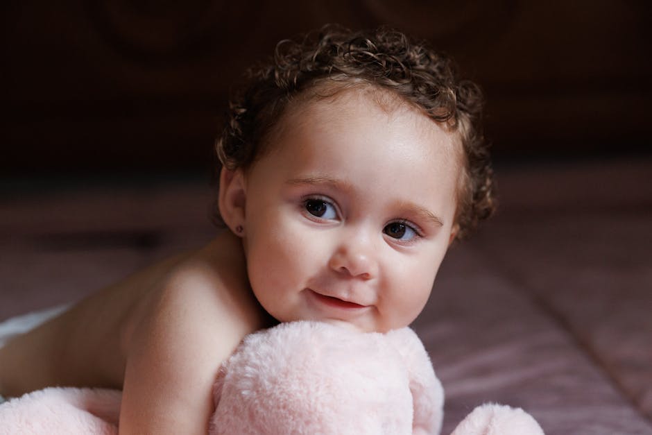 A baby engages with a soft hanging toy featuring crinkly textures and a baby-safe mirror.