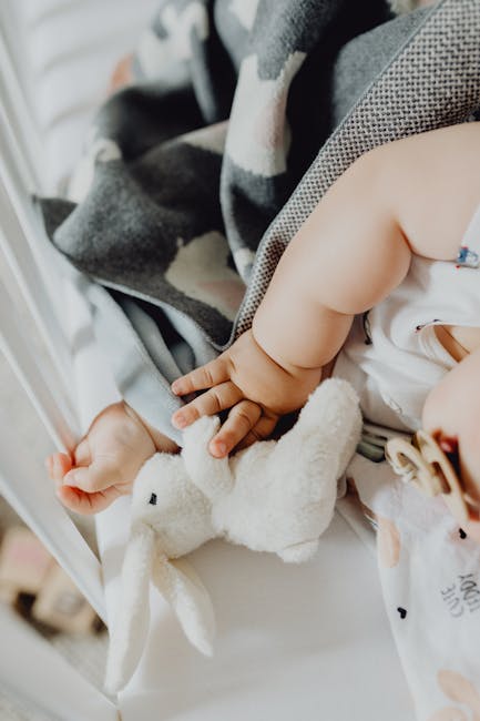 A parent gently placing a plush sheep sleep aid in a baby's crib.