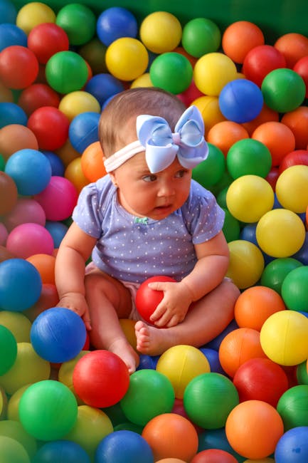 A variety of containers filled with different sensory materials like water beads, pom poms, and colorful pasta arranged on a table.